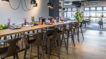 Un comedor moderno con una larga mesa de madera, taburetes de bar e iluminación colgante.