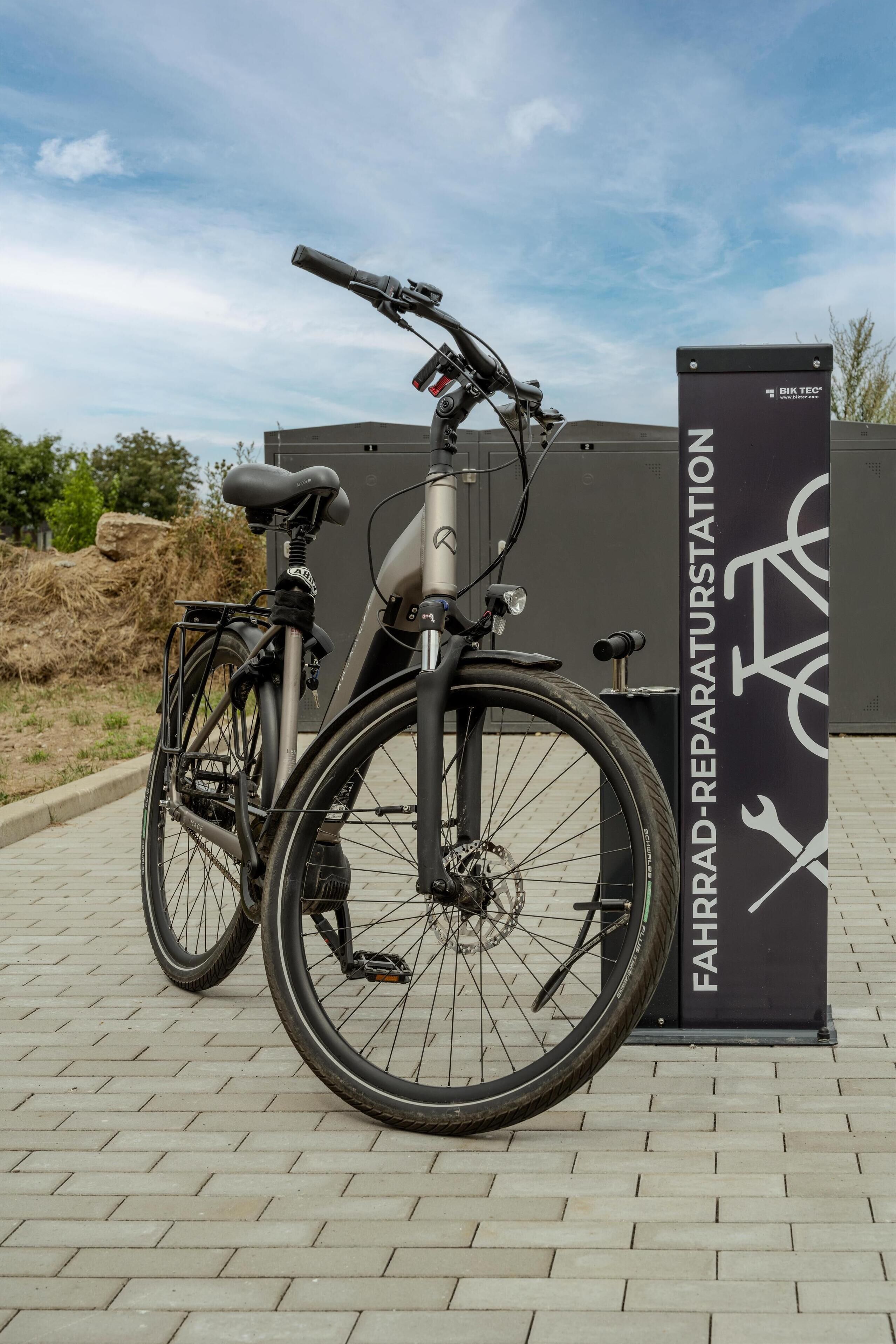 A stationary bicycle parked next to a sign that reads "FAHRRAD-REPARATURSTATION".