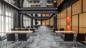 A conference room with tables and chairs, large windows, and a patterned ceiling. - Park Inn By Radisson Wismar (Wismar)