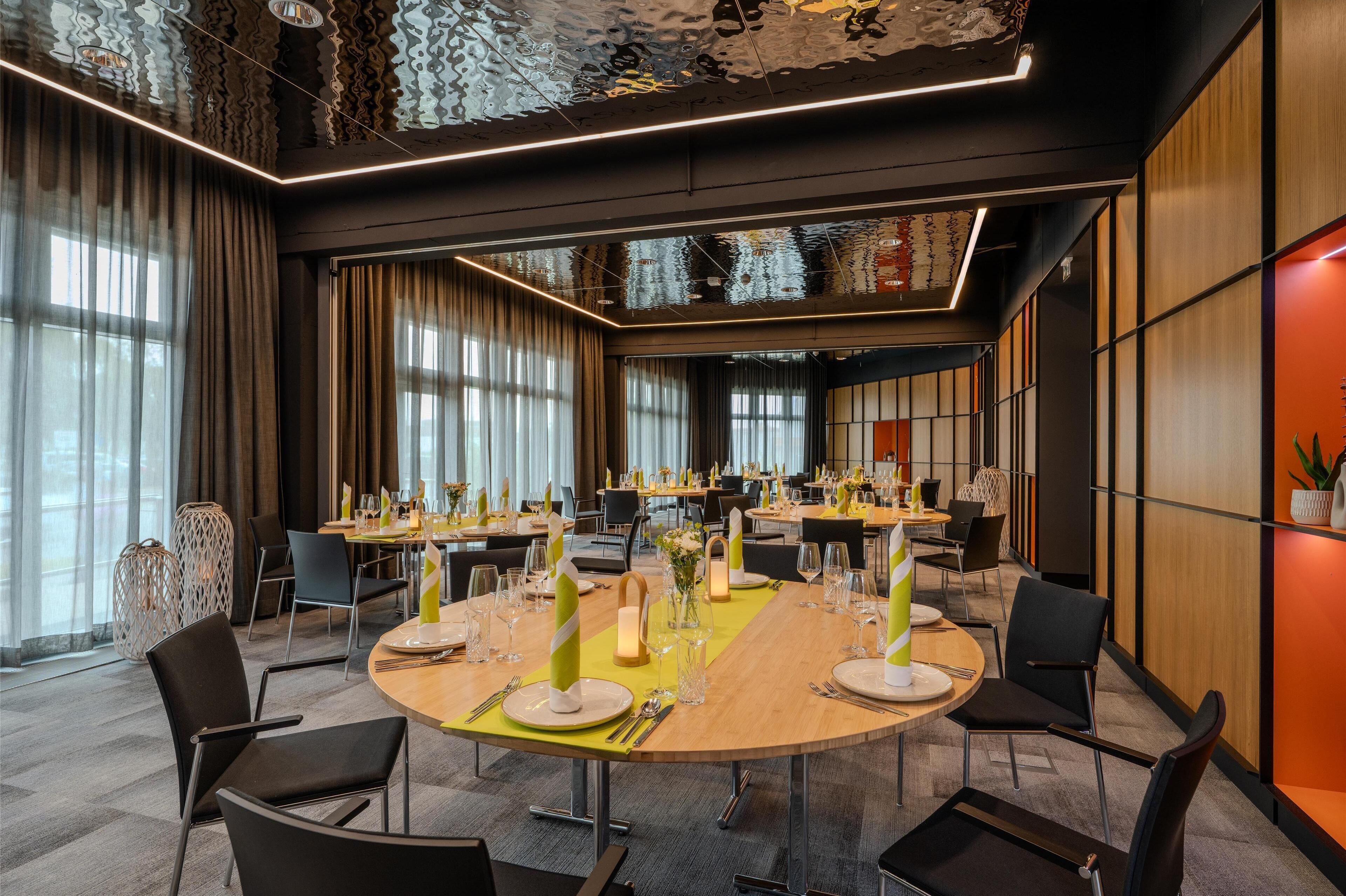 A modern conference room with round tables, chairs, and a high ceiling with patterned design.
