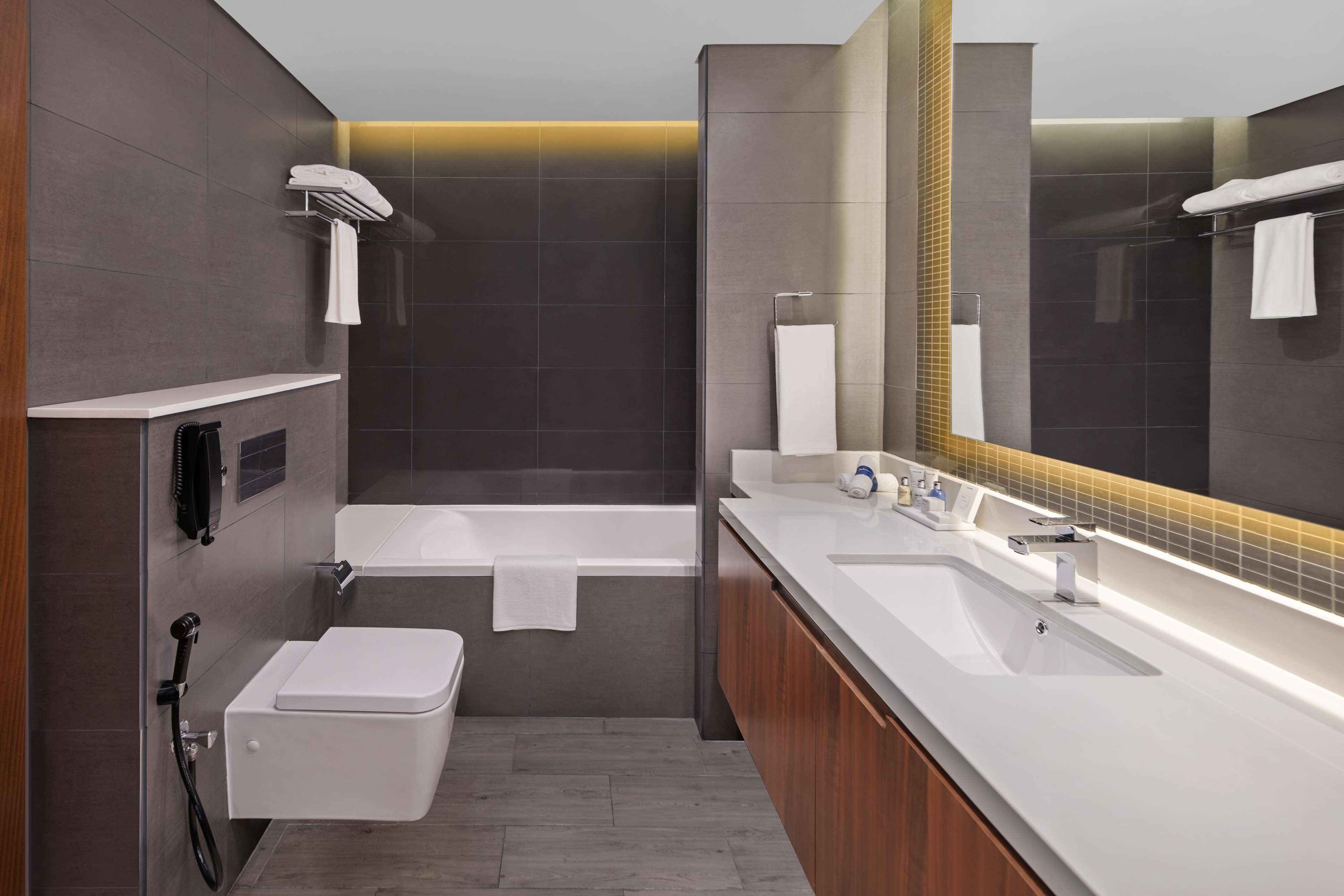 A modern bathroom with a bathtub, a toilet, a sink, and a large mirror.