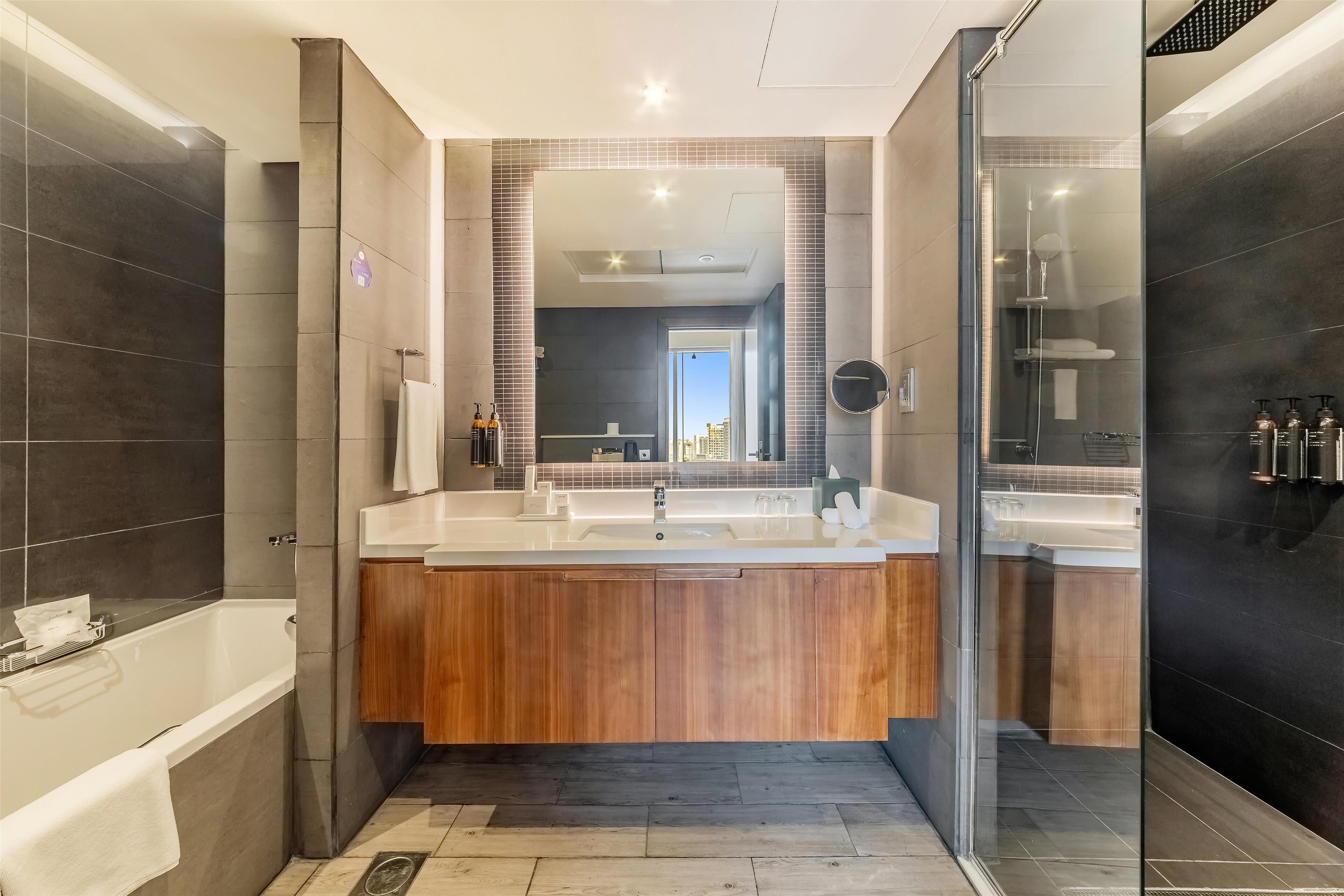 Une salle de bain moderne avec une grande baignoire, un meuble-lavabo en bois et une cabine de douche en verre.