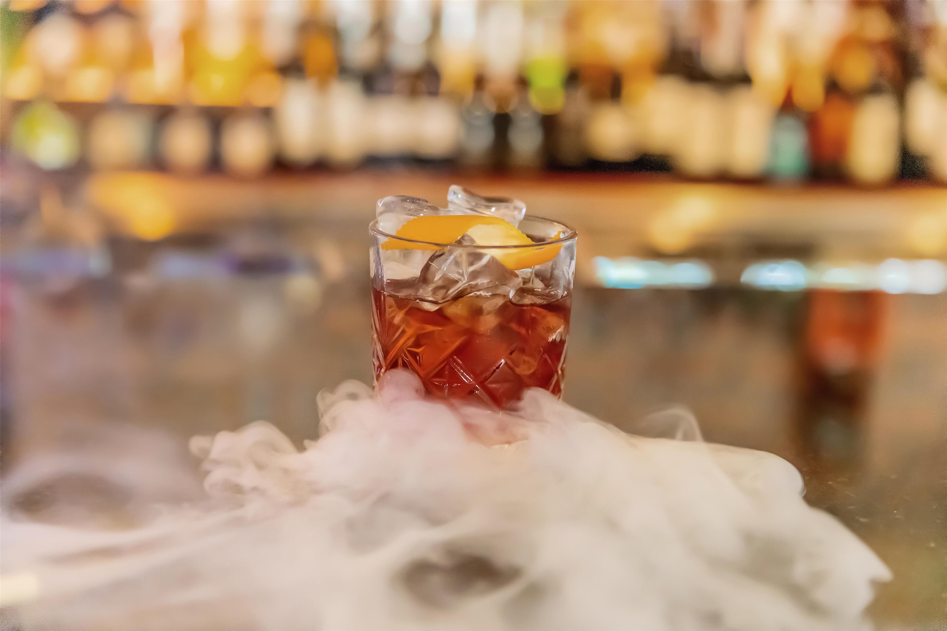 A glass of iced tea with an orange slice on a bar counter.