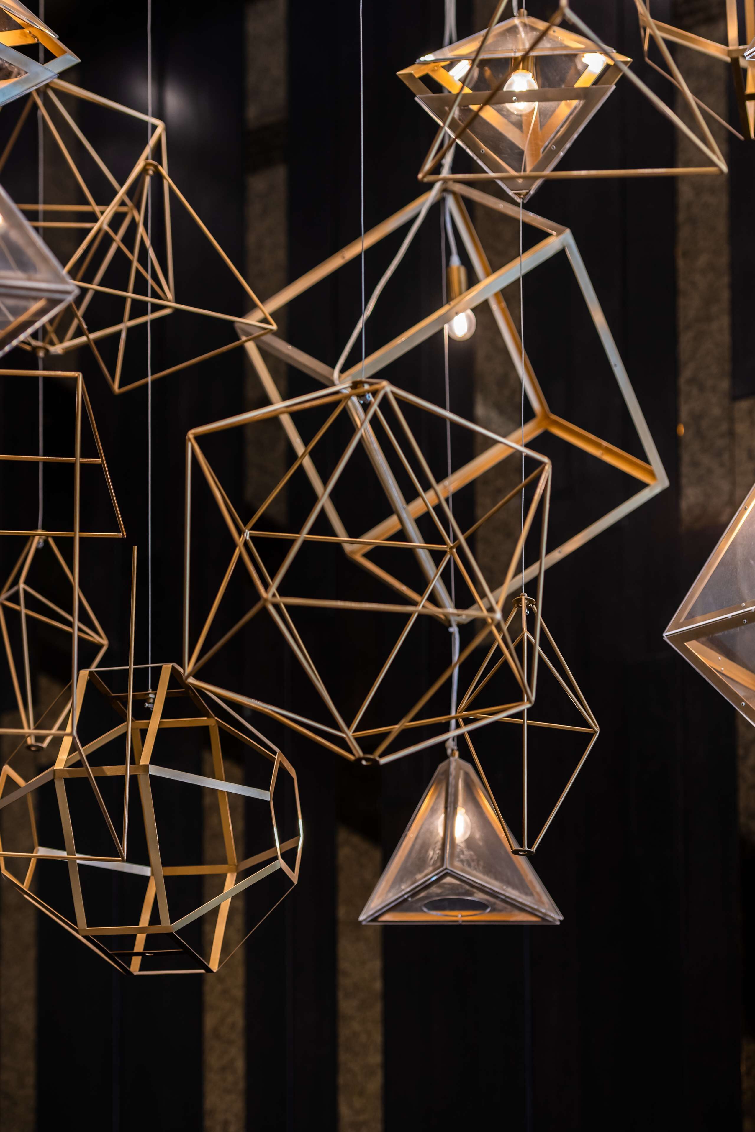 A collection of geometric hanging light fixtures with multiple bulbs.