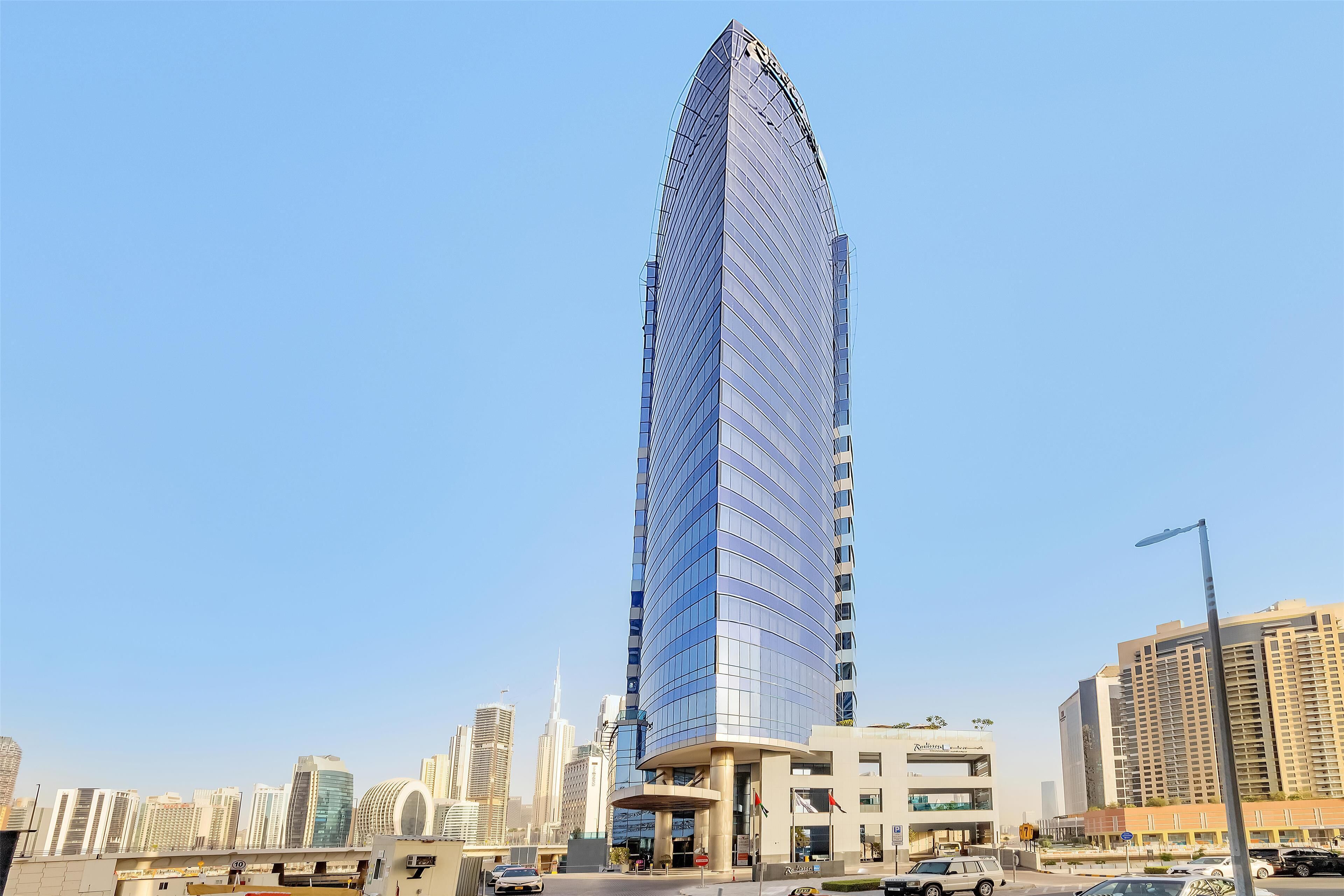 A tall, modern skyscraper with a curved glass facade, surrounded by other high-rise buildings in an urban setting.