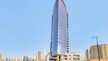 A tall, modern skyscraper with a curved glass facade, surrounded by other high-rise buildings in an urban setting.
