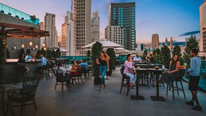 An outdoor dining area with tables and chairs, surrounded by tall buildings and a clear sky. - Radisson Blu Hotel, Dubai Canal View (Dubai)