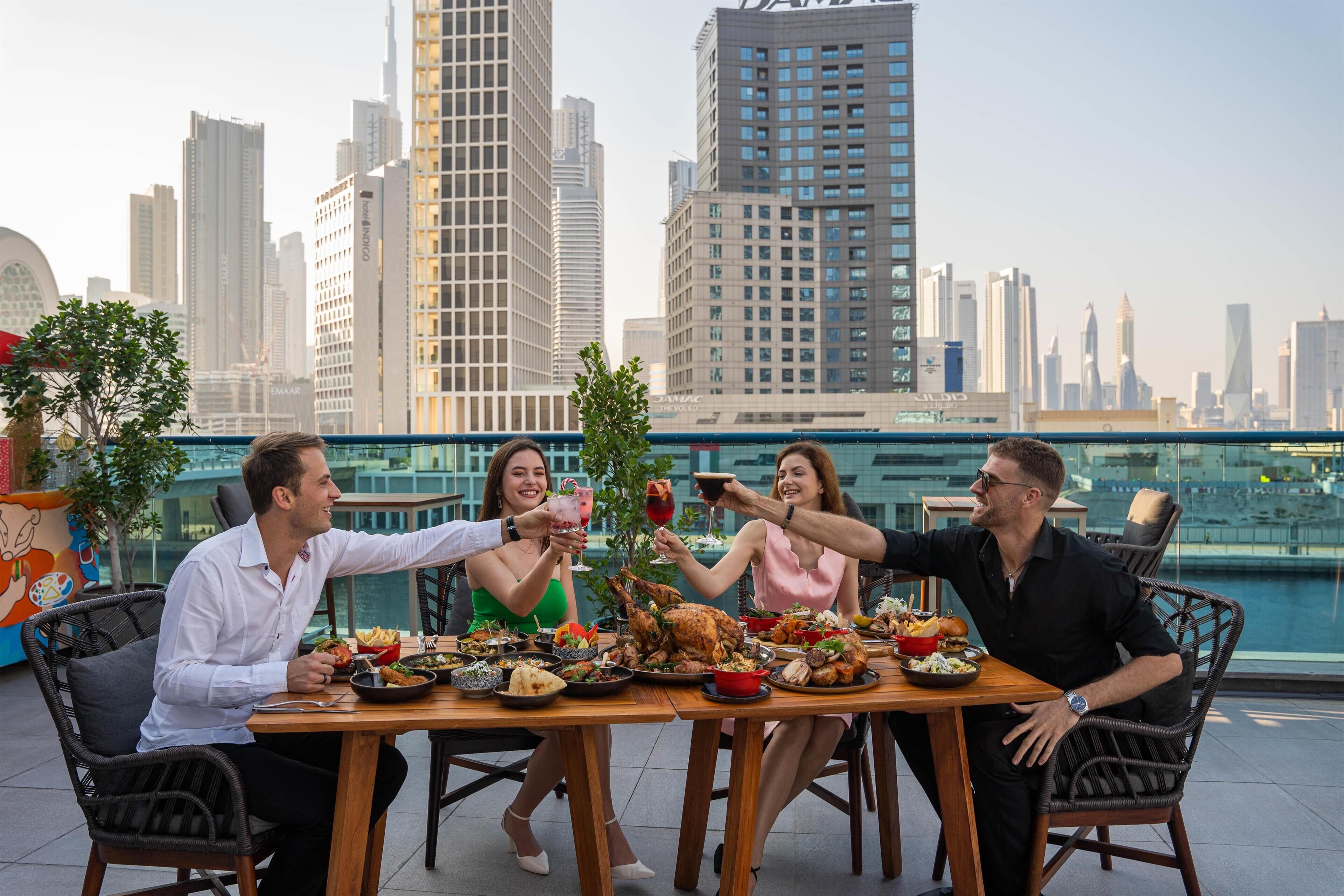 A group of people dining at a table with a cityscape view in the background.