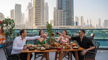 A group of people dining at a table with a cityscape view in the background.