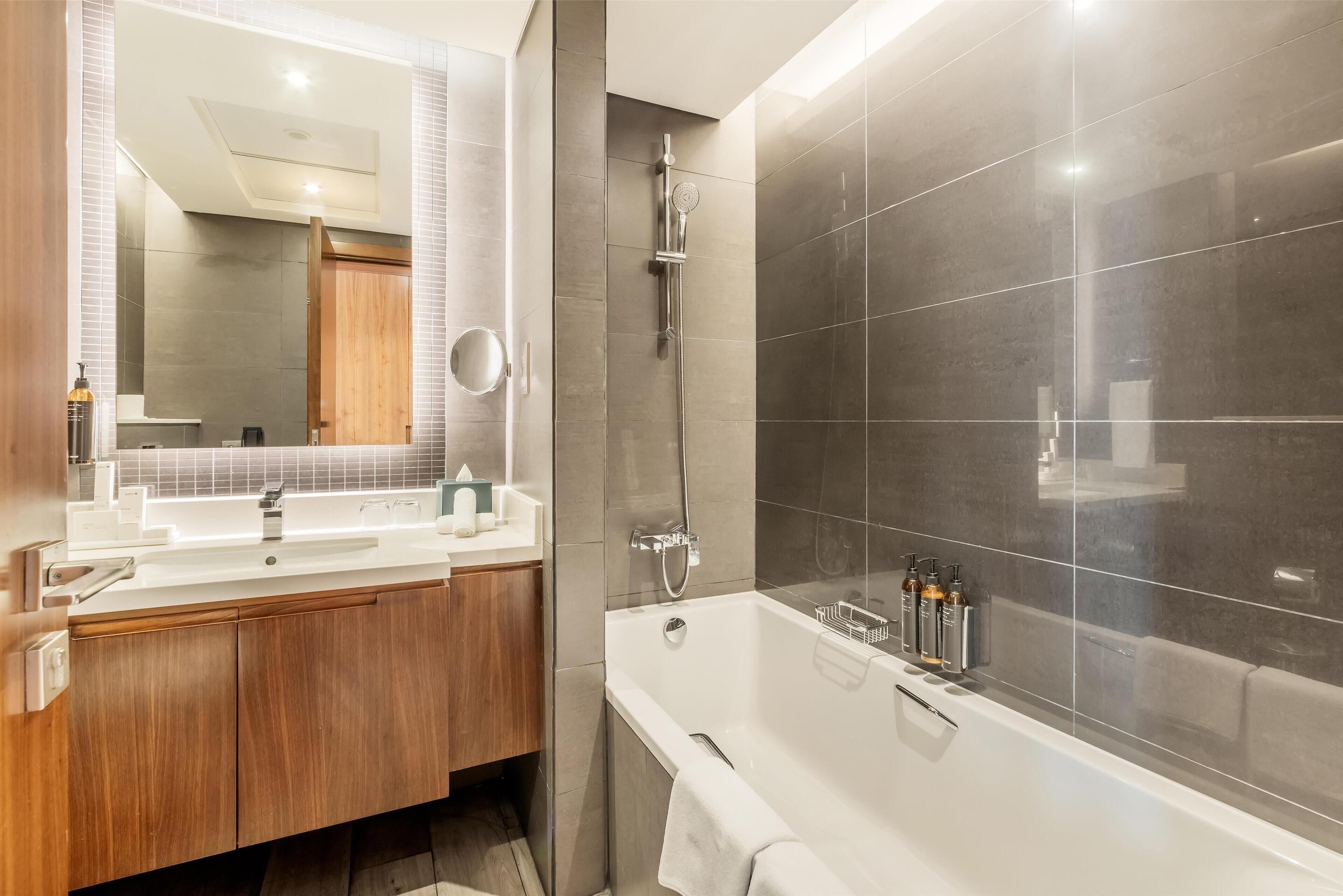 Une salle de bain moderne dotée d’un meuble-lavabo à deux vasques, d’un grand miroir, d’une baignoire sur pieds et d’un espace douche.