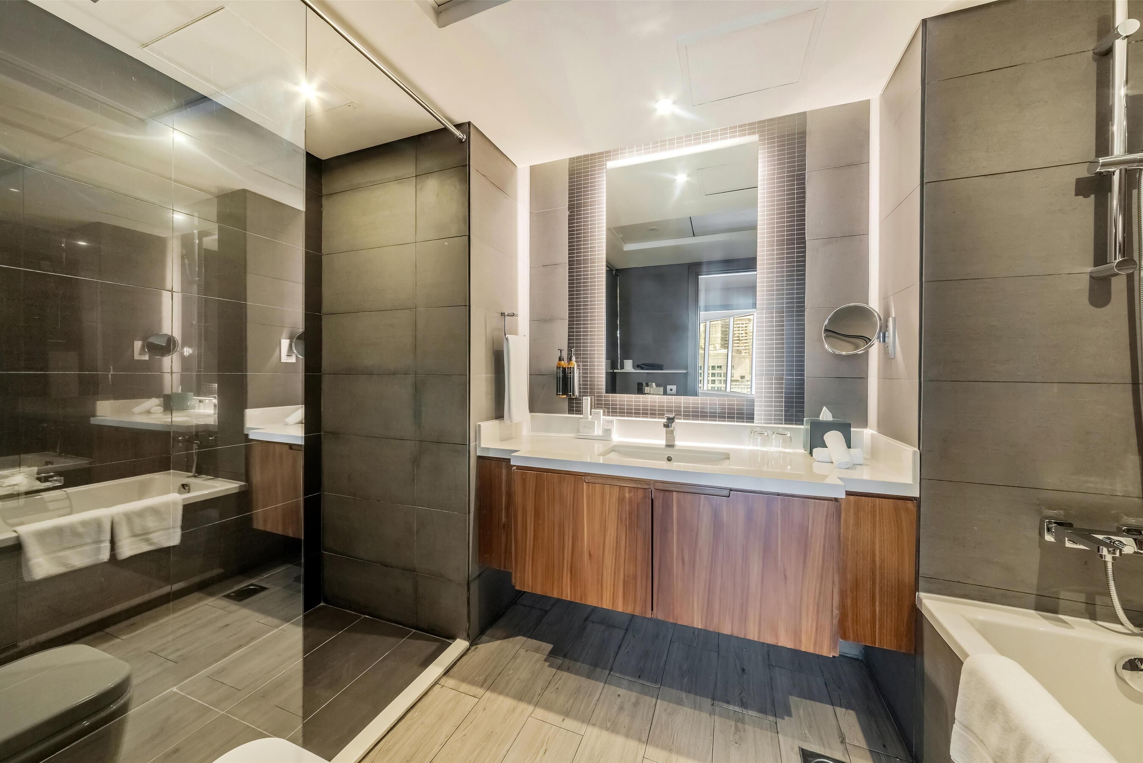 A modern bathroom with a glass-enclosed shower, a large mirror, and wooden cabinets.