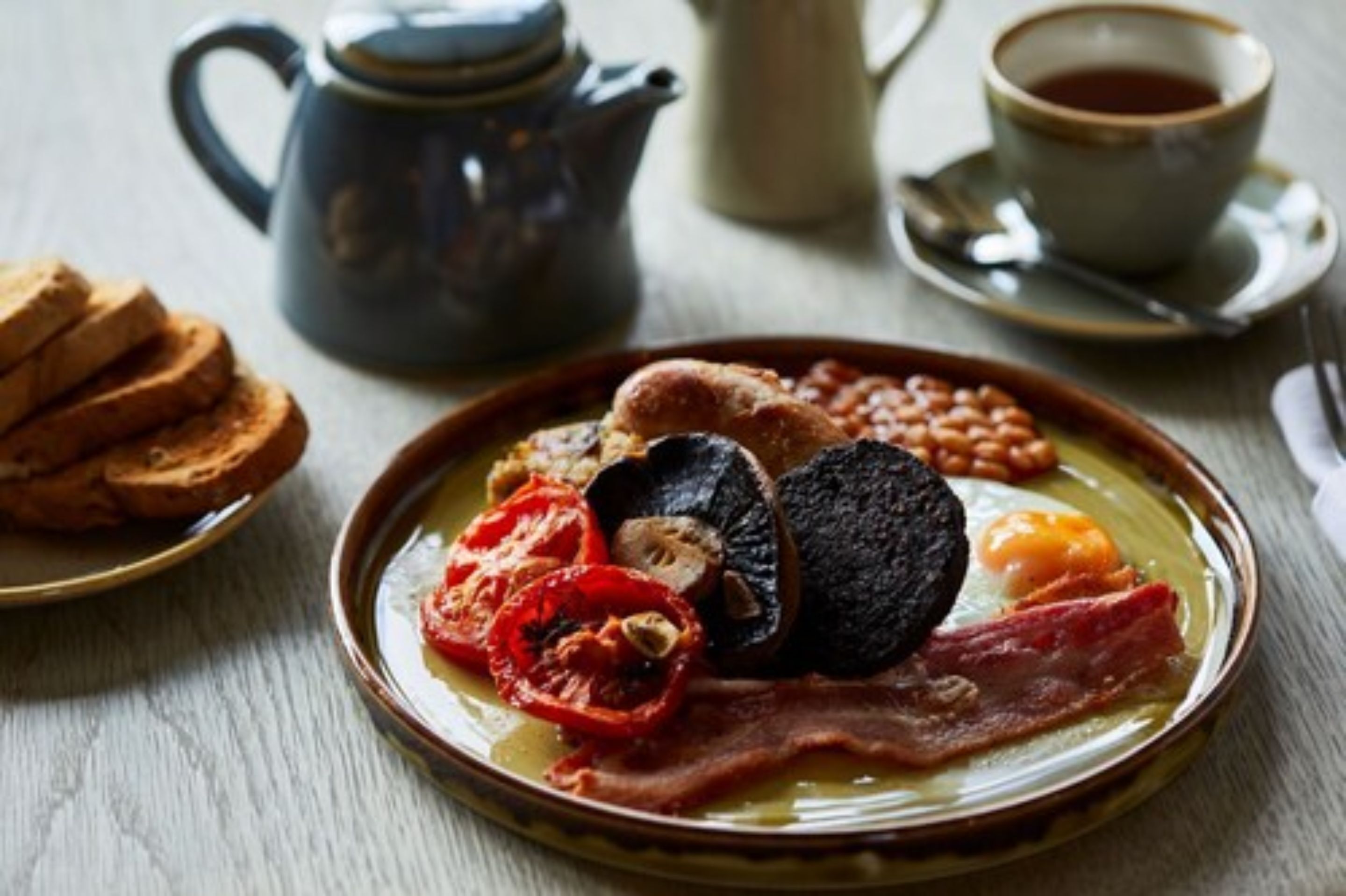 A breakfast plate with eggs, bacon, mushrooms, tomatoes, and beans.