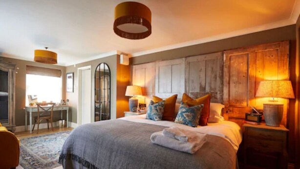 A bedroom with a large bed, bedside lamps, and a wooden headboard.