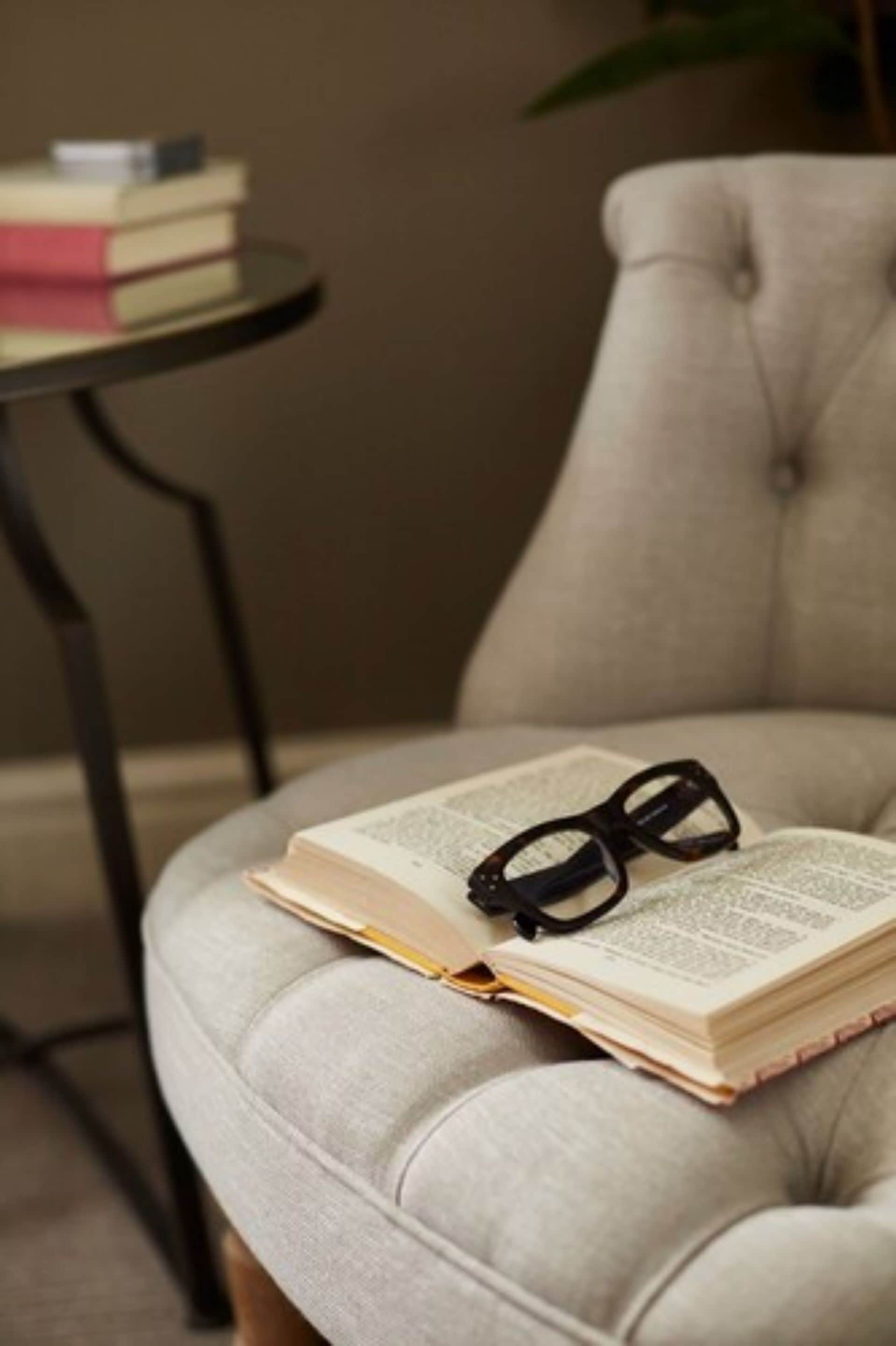 A tufted armchair with a book and glasses on it.