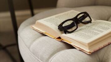 A tufted armchair with a book and glasses on it.