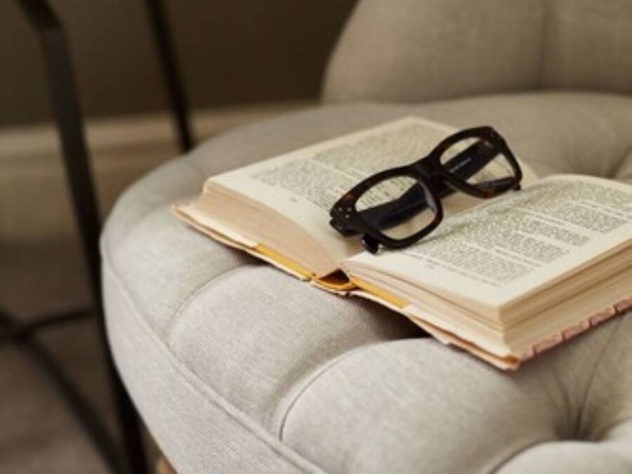 A tufted armchair with a book and glasses on it.