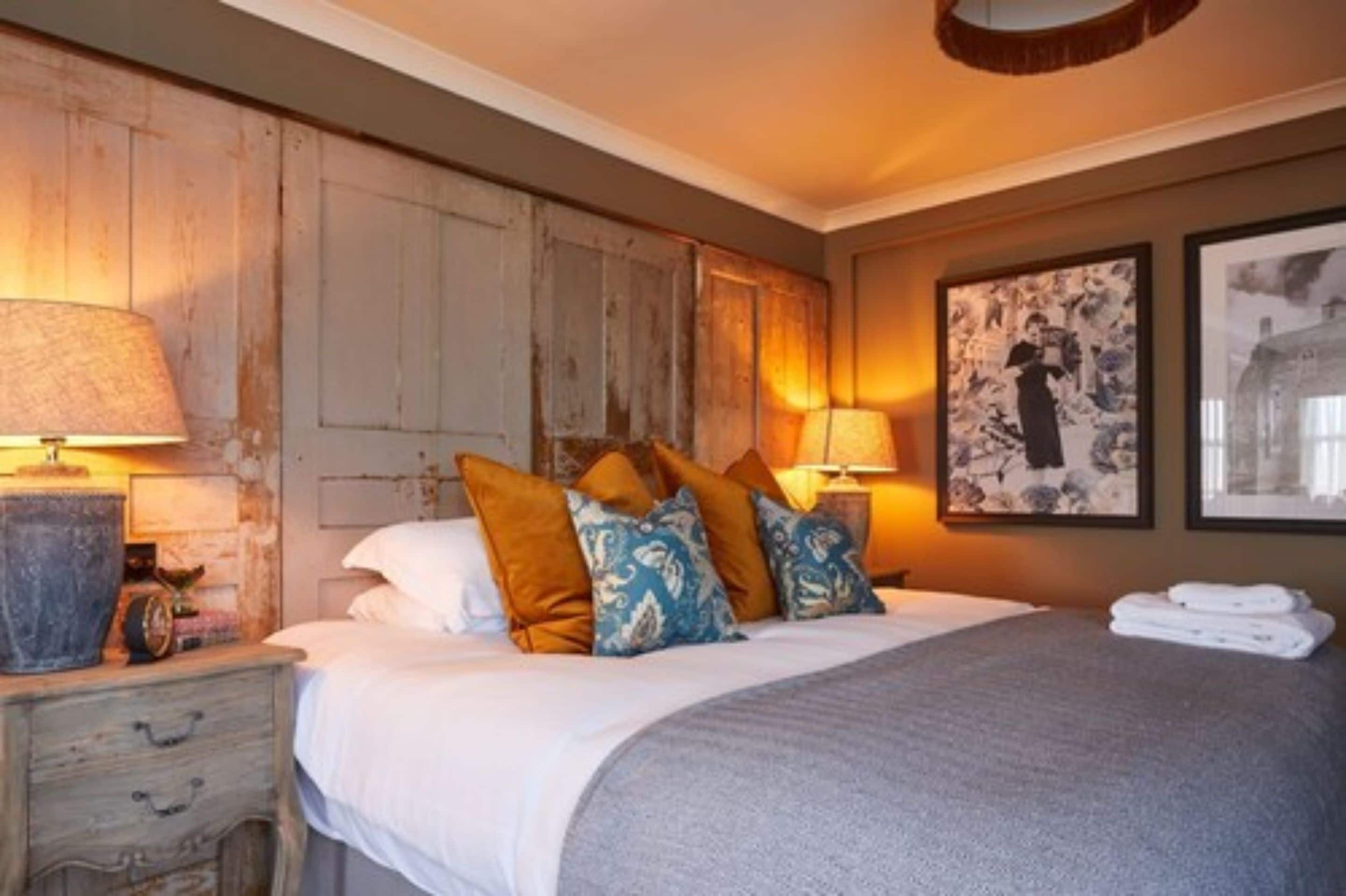 Un dormitorio con una cama grande, dos mesitas de noche y lámparas de pared.