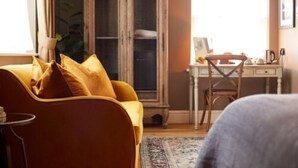 A room with a yellow sofa, a wooden cabinet, a desk, and a chair.