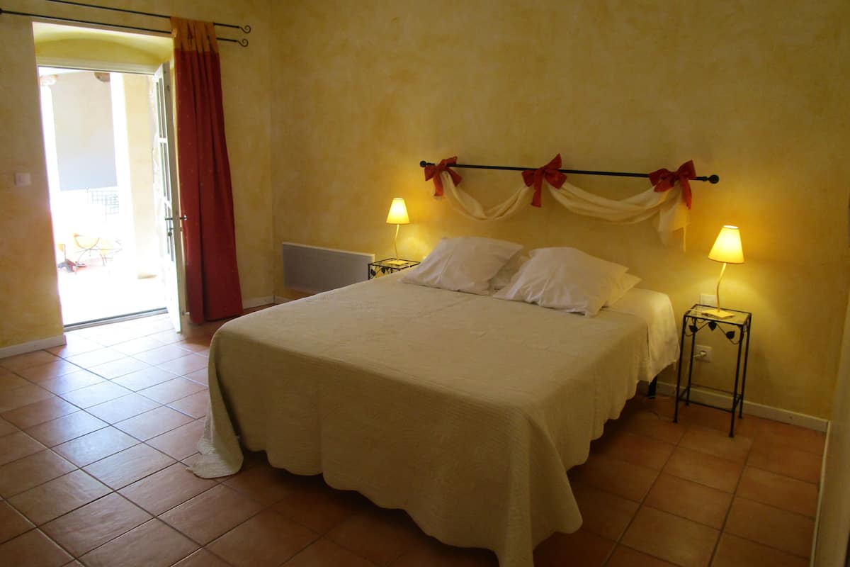 Ein Schlafzimmer mit einem Bett, zwei Nachttischlampen, einem Vorhang und einer Heizung.