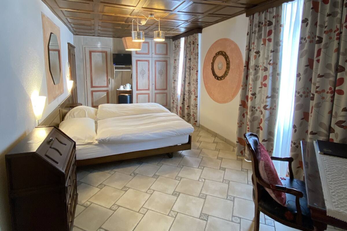 A hotel room with a bed, a dresser, a chair, a desk, and a mirror.