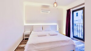 A modern hotel room with a large bed, bedside tables, a built-in air conditioning unit, and a balcony with a view. - Kas Sanisu Pansiyon (Kas)