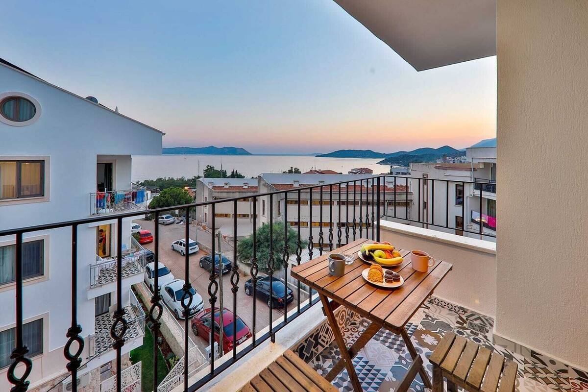 A balcony with a table set for breakfast, overlooking a street and a body of water.