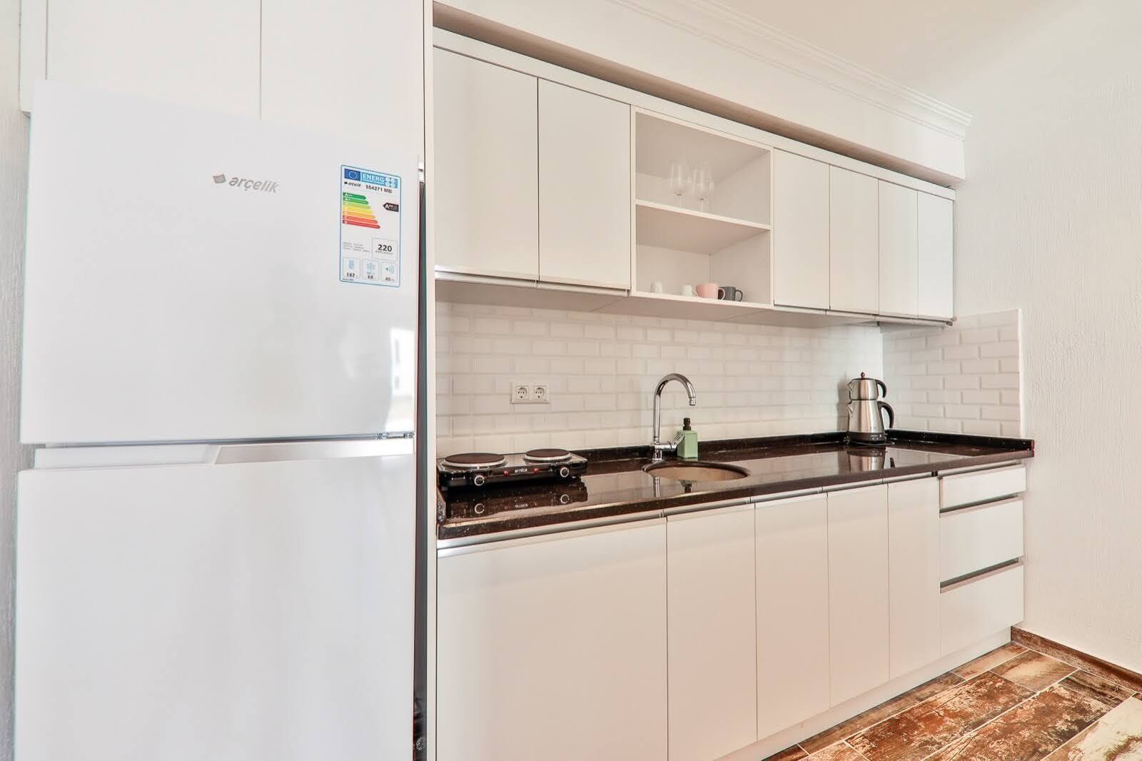 A modern kitchen with white cabinetry, a built-in oven, and a stainless steel sink.