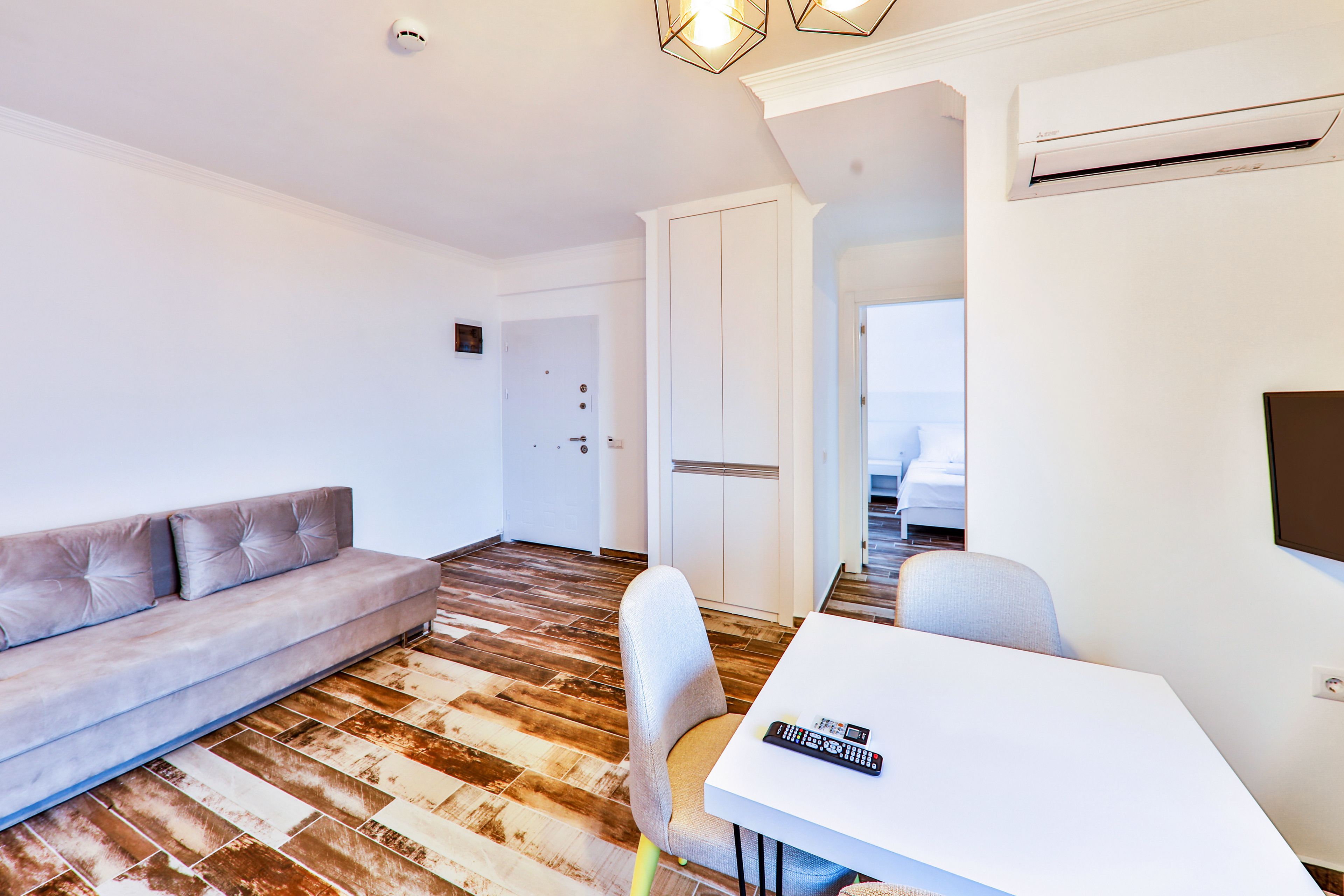 A modern hotel room with a sofa, a dining table, and a TV.