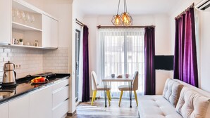 A modern kitchen with white cabinets, a dining area with a table and chairs, and a living area with a sofa. - Kas Sanisu Pansiyon (Kas)