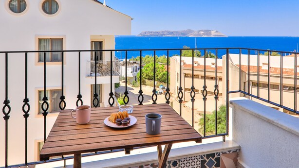 A balcony with a wooden table, a pink mug, and a plate of pastries. - Kas Sanisu Pansiyon (Kas)