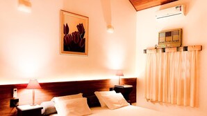 A hotel room with a large bed, two bedside tables with lamps, a wall-mounted air conditioner, and a framed picture above the bed. - Parque Hotel Holambra (Holambra)