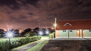 A building with a green facade and a red roof, surrounded by well-maintained hedges and a gravel path. - Parque Hotel Holambra (Holambra)