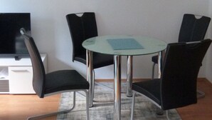 A modern room with a glass-top table surrounded by four black chairs, a flat-screen TV, and a framed abstract artwork on the wall. - Wohnung im Zentrum des Ruhrgebiets (Castrop-Rauxel)