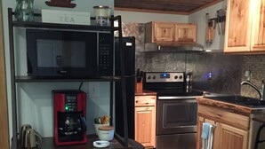 Une cuisine avec des meubles de rangement en bois, un four à micro-ondes, une machine à café et une cuisinière.