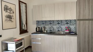 A modern kitchen with light wood cabinets, a patterned backsplash, and stainless steel appliances. - B&B Il Torchio (Urbino)