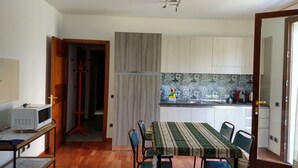 A compact kitchen with a dining area, wooden cabinets, a microwave, and a patterned tablecloth. - B&B Il Torchio (Urbino)