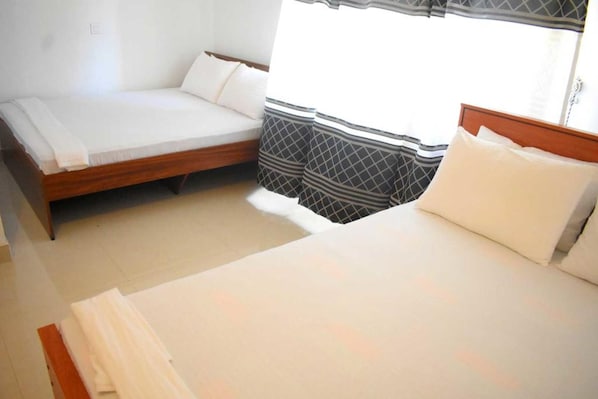 Un dormitorio con cama, sofá y ventana con cortinas.