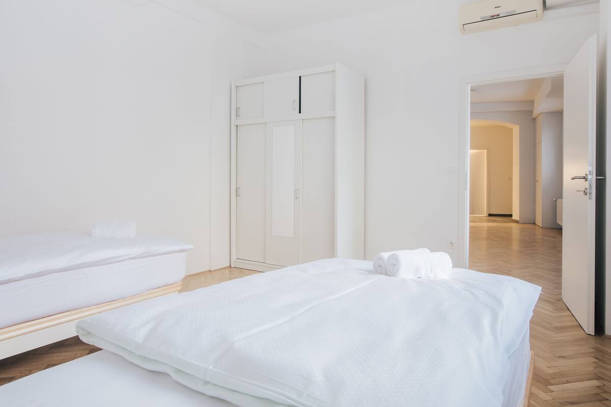 Een moderne hotelkamer met een groot bed, een kleiner bed en een kledingkast.