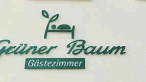 A logo with a bed and the text "Guiner Baum Gästezimmer". - Grüner Baum (Langenau)