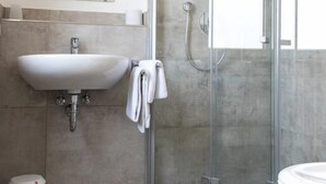 A modern bathroom with a glass shower enclosure, a sink, and a toilet. - Grüner Baum (Langenau)