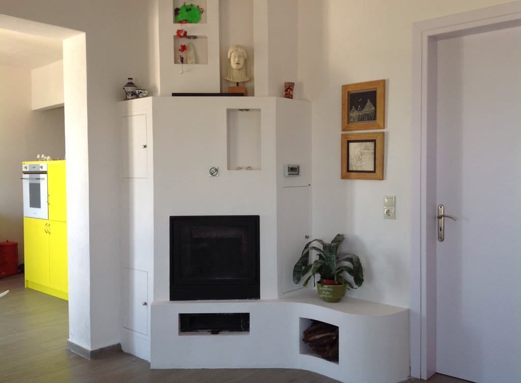 Un salon moderne avec un téléviseur encastré, une petite plante et des œuvres d’art accrochées au mur.
