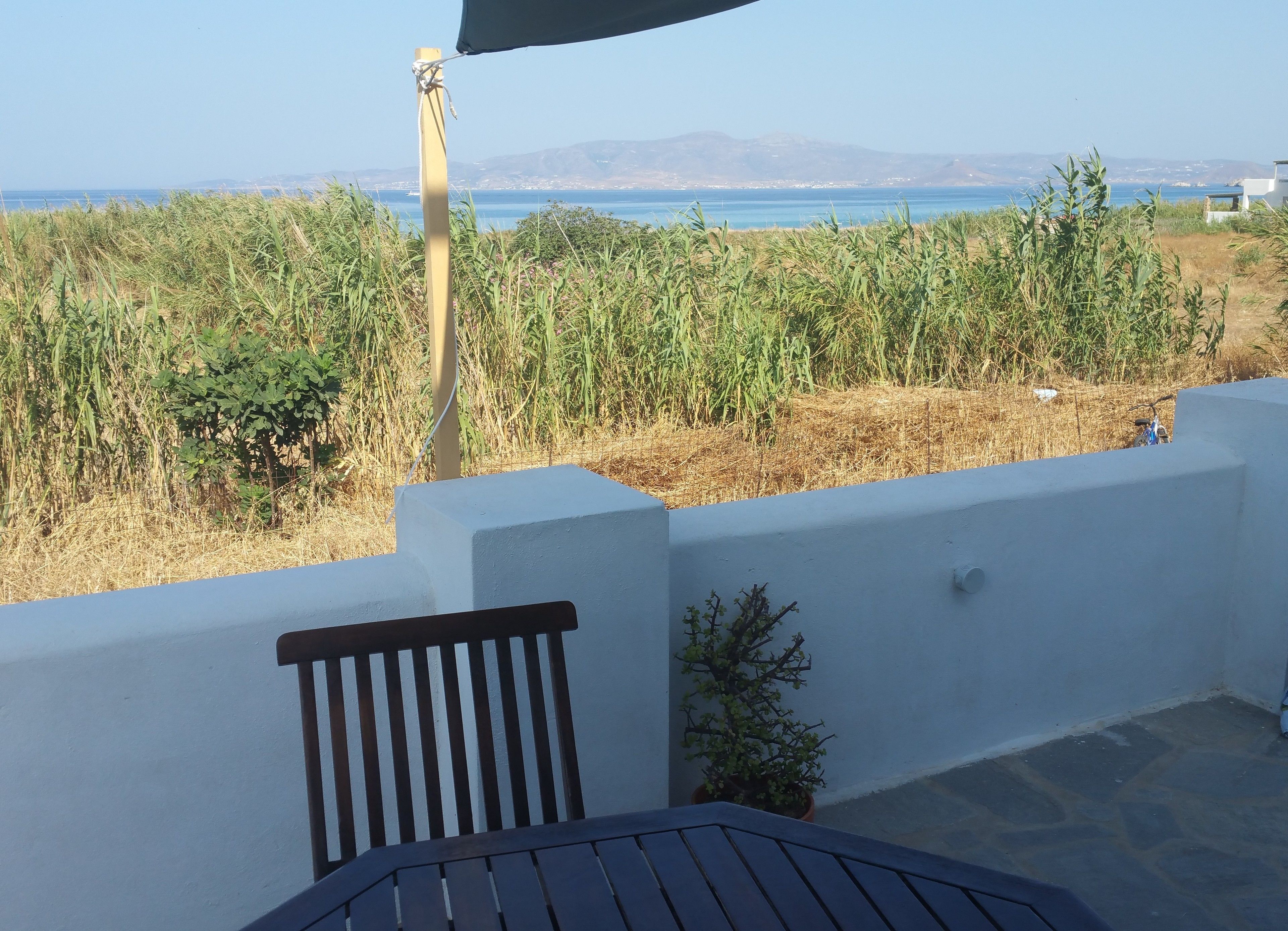 A terrace with a view of the sea and mountains, featuring a table and a bench.