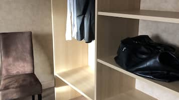 A room with a wooden wardrobe, a chair, and a black bag on the shelves.