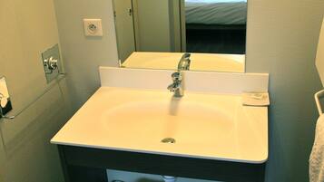 A bathroom with a white sink, a mirror, a towel rack, and a small trash bin.