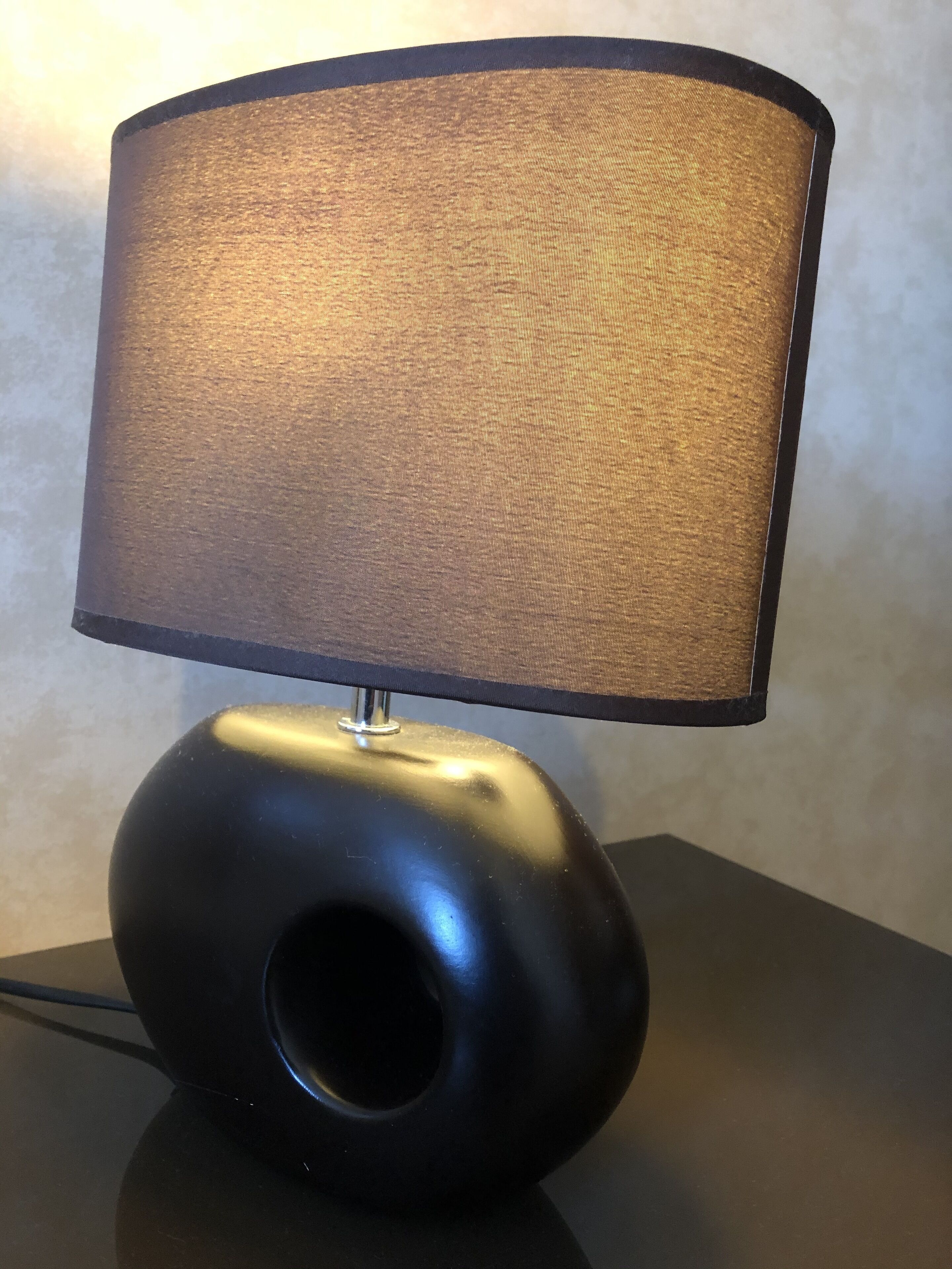 A modern table lamp with a cylindrical base and a fabric shade.