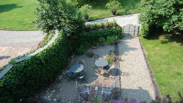 Een terras buiten met een grindpad, omringd door weelderig groen en potplanten.