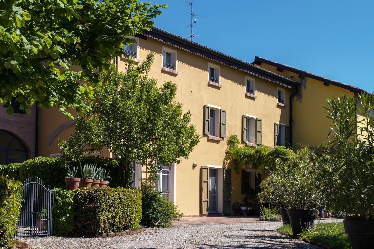 Un bâtiment jaune avec de nombreuses fenêtres et une porte, entouré de verdure et bordé d’un chemin de gravier.