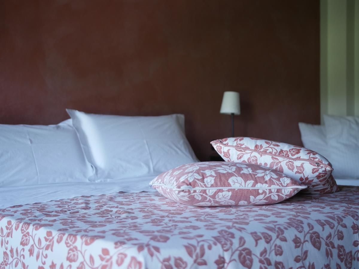 Een bed met wit en roze bloemenbeddengoed, een houten hoofdbord en een bedlampje.