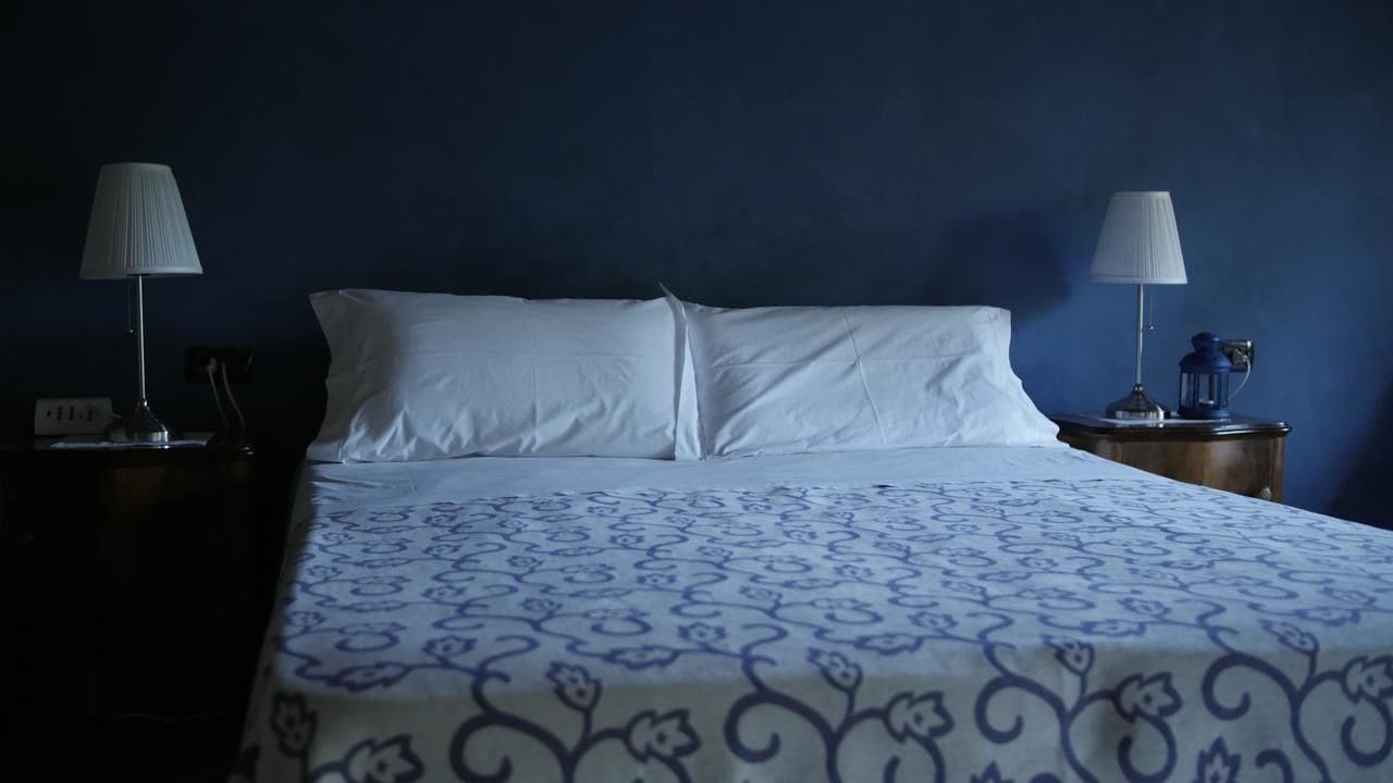 A hotel room with a bed, two bedside tables, and lamps.