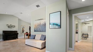 Een ruime woonkamer met een piano, een bank en een groot abstract schilderij.